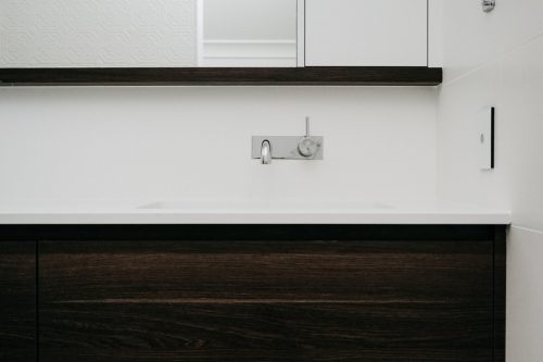modern white basin with dark drawers and large mirror