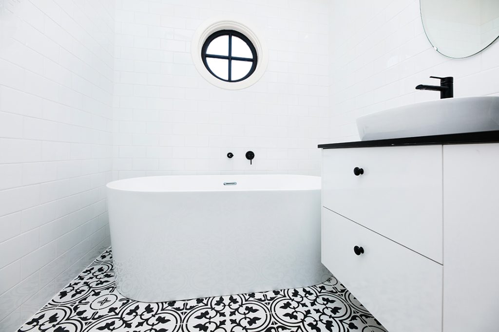 white and black bathroom, small round window above
