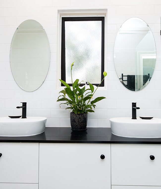 black and white sinks with oval mirrors above