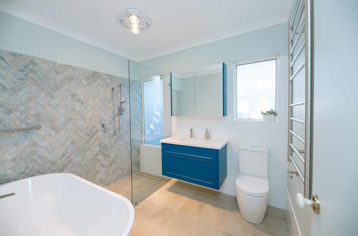 bright blue cupboard in spacious bathroom with large bath