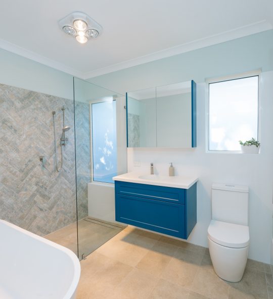 bright blue cupboard in spacious bathroom with large bath