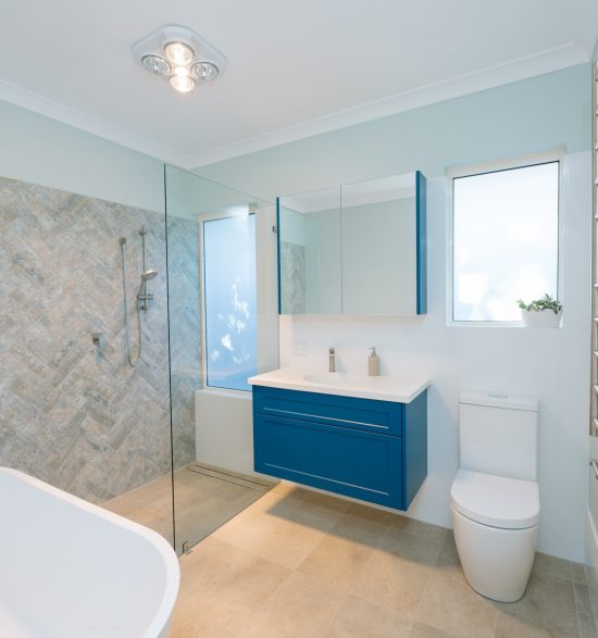 bright blue cupboard in spacious bathroom with large bath