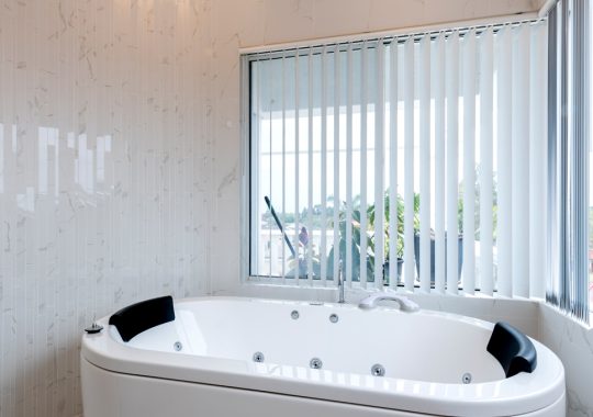 large spa bath with venetian blinds behind