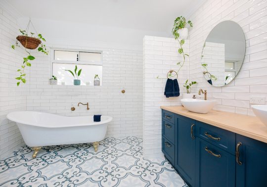 blue cupboards in a white and blue bathroom, bath in back