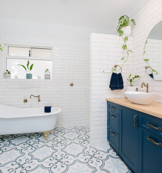 blue cupboards in a white and blue bathroom, bath in back