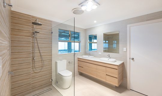 Narrow bathroom with twin vanities and large shower
