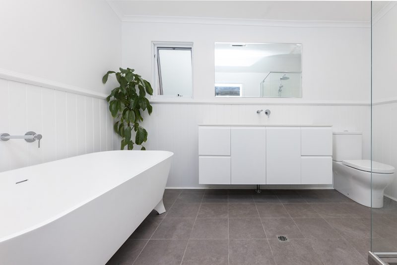 A large all-white bathroom with grey tiling