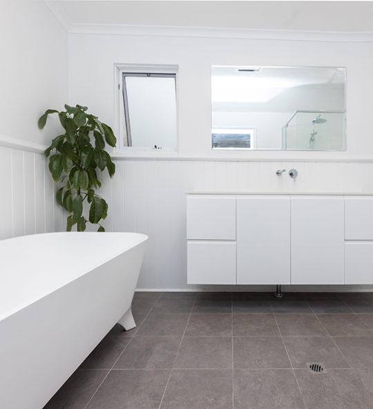 A large all-white bathroom with grey tiling