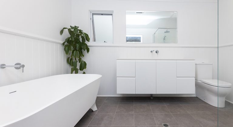 A large all-white bathroom with grey tiling