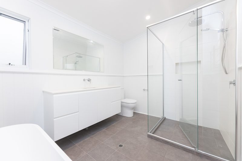 This new bathroom features an enclosed shower with glass panels and a hand-held shower head