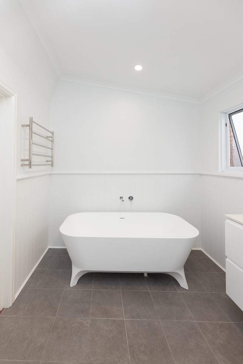 A modern freestanding bathtub with heated towel rails