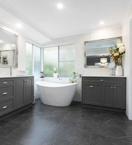 The new renovated bathroom, which features a modern freestanding bathtub by the windows, in between two refurbished vanities