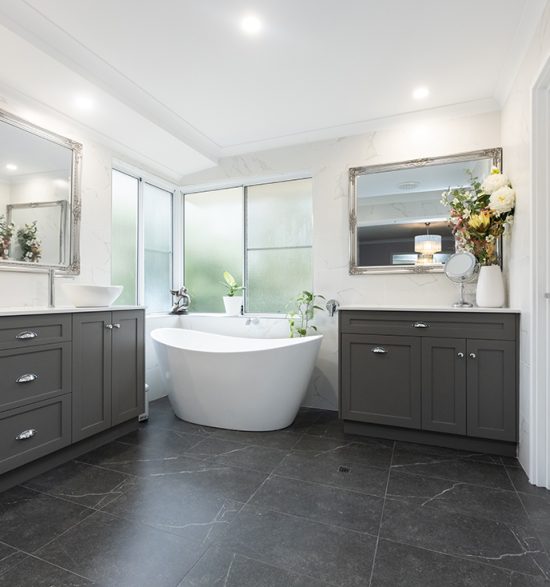 The new renovated bathroom, which features a modern freestanding bathtub by the windows, in between two refurbished vanities