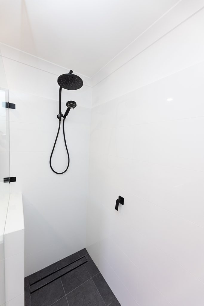 A black handheld shower with a rain-shower head is installed in a newly-renovated bathroom