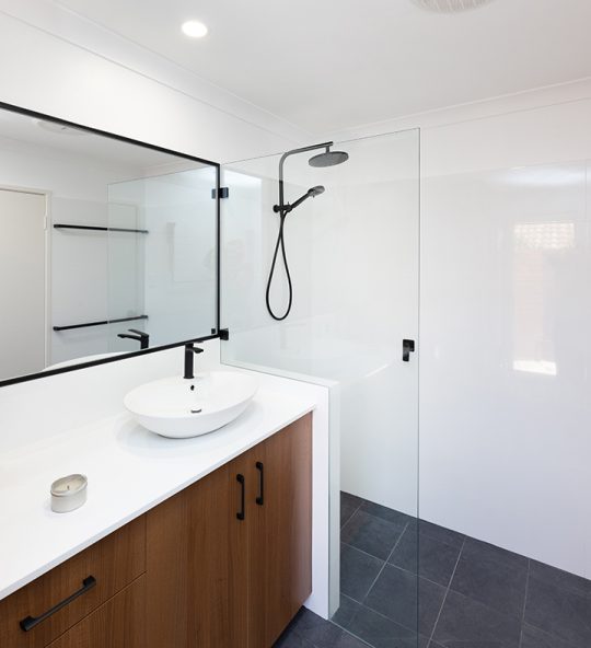 A newly-renovated bathroom with dark-wood cabinets and black tapware