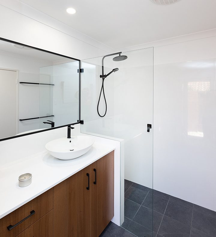 A newly-renovated bathroom with dark-wood cabinets and black tapware