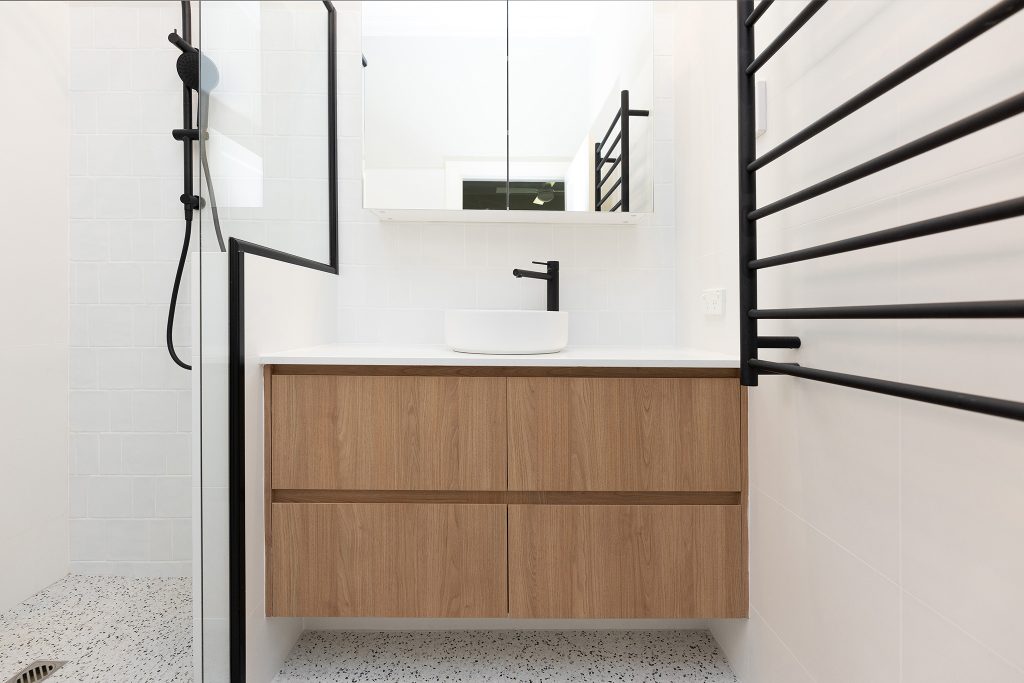 A newly-renovated bathroom with a floating vanity and a matte black towel rail, tap ware, and shower head