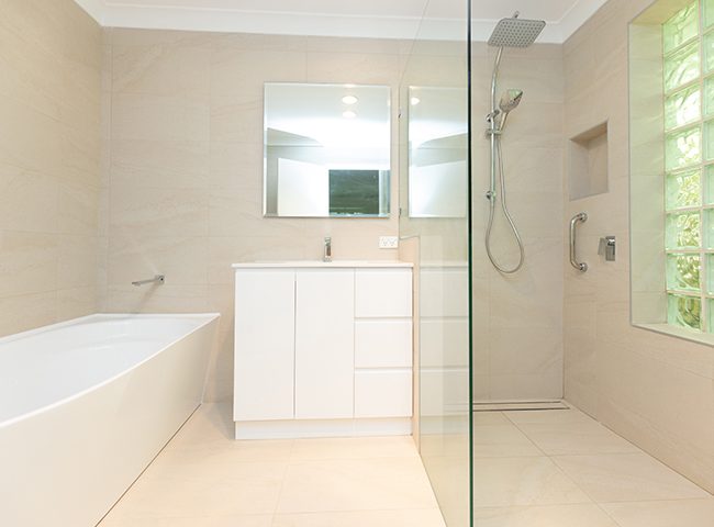 A bright, newly-renovated bathroom with cream tiles and a walk-in shower