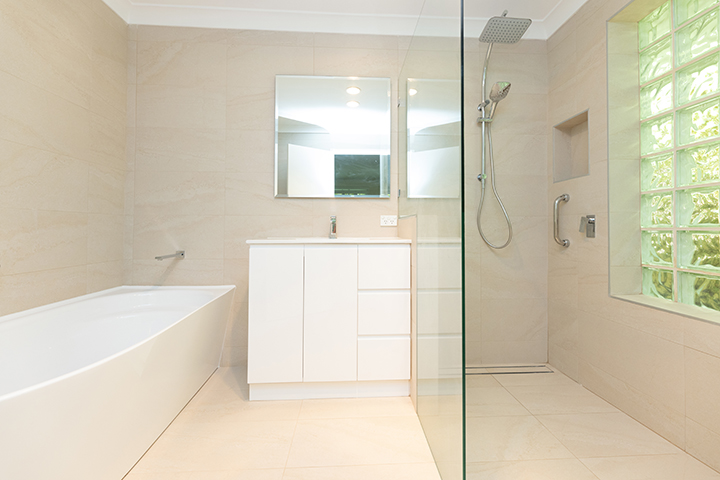 A bright, newly-renovated bathroom with cream tiles and a walk-in shower