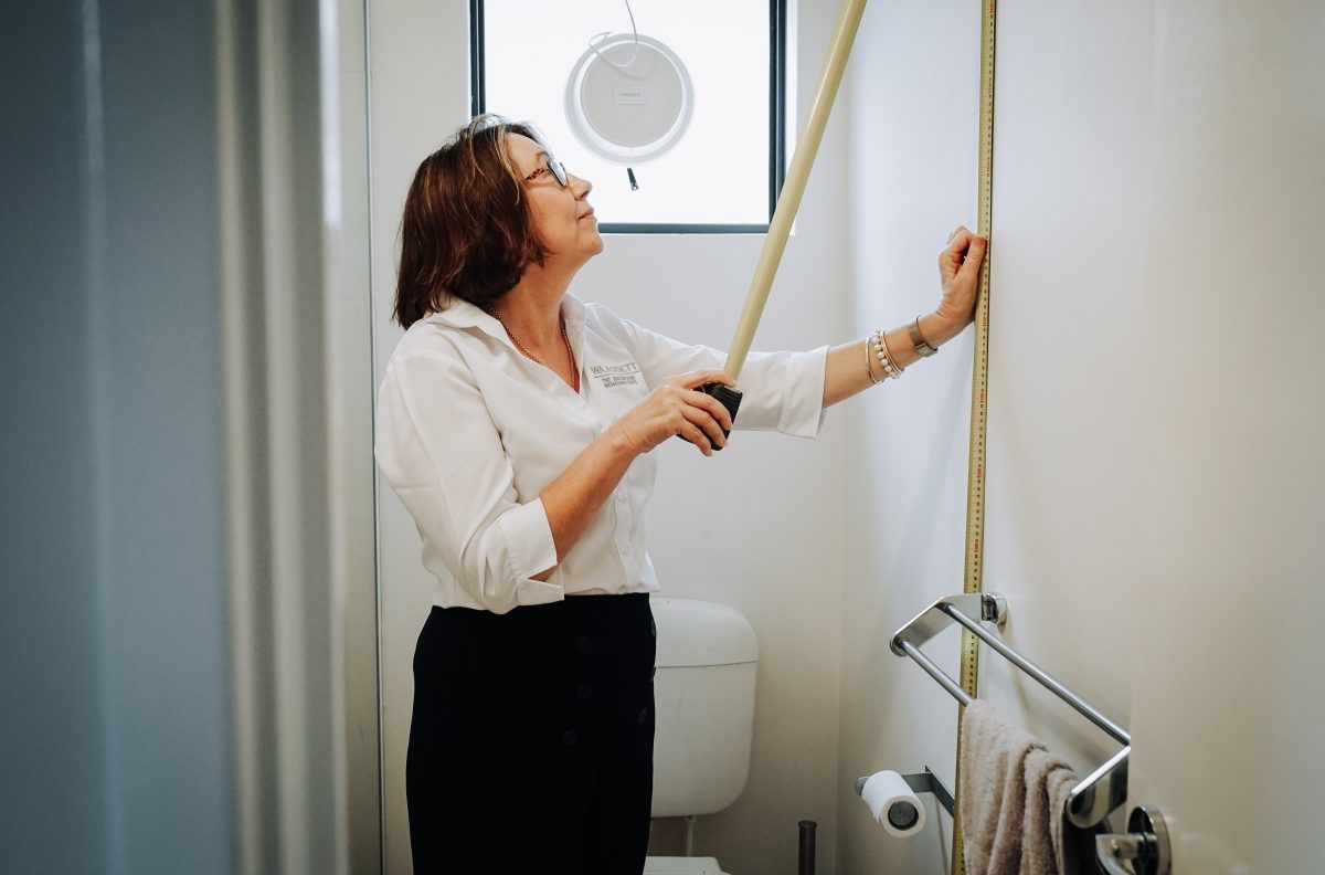 A woman measures the height of a bathroom wall