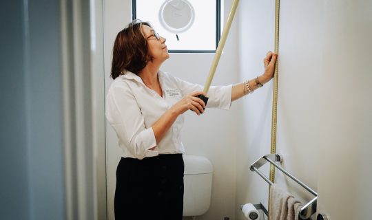 A woman measures the height of a bathroom wall