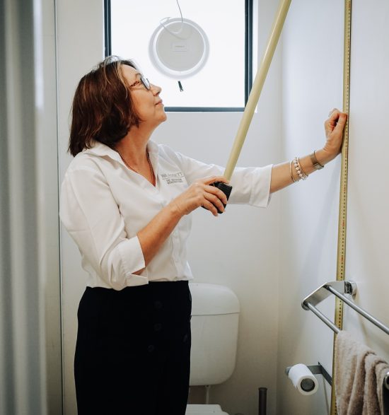 A woman measures the height of a bathroom wall