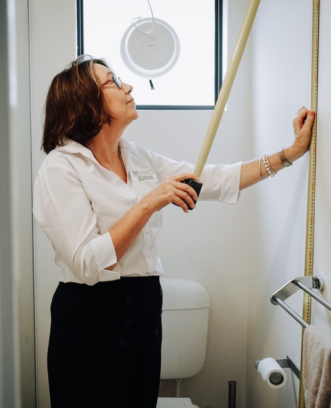 A woman measures the height of a bathroom wall