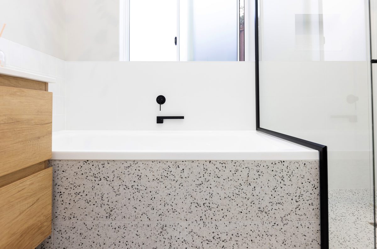 A bath with black finishings and marbled exterior, white wall tile.