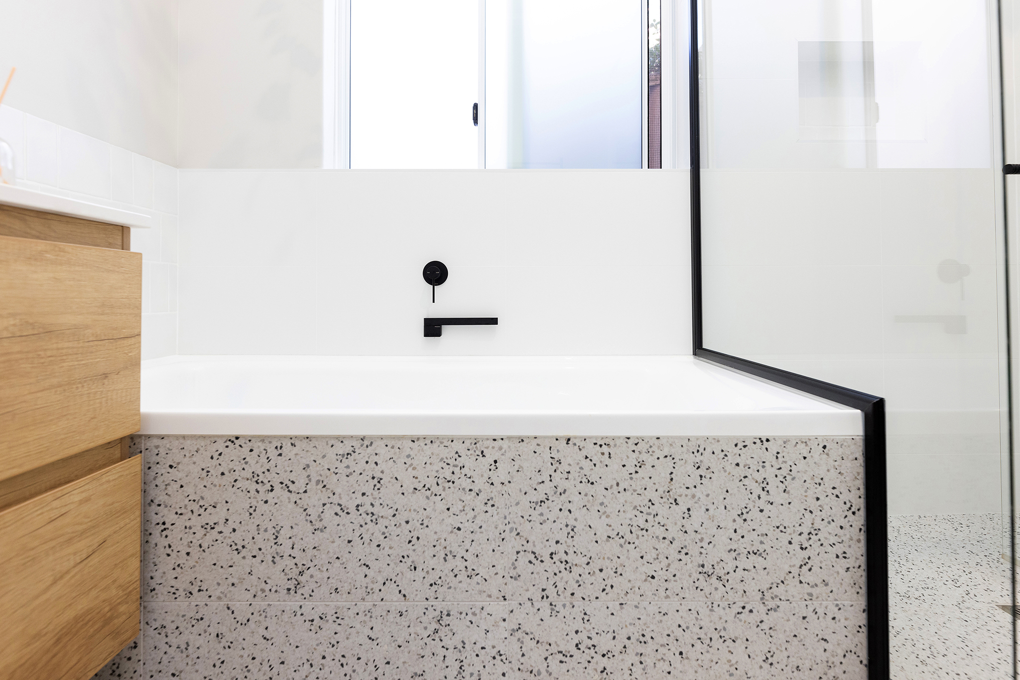 A bath with black finishings and marbled exterior, white wall tile.