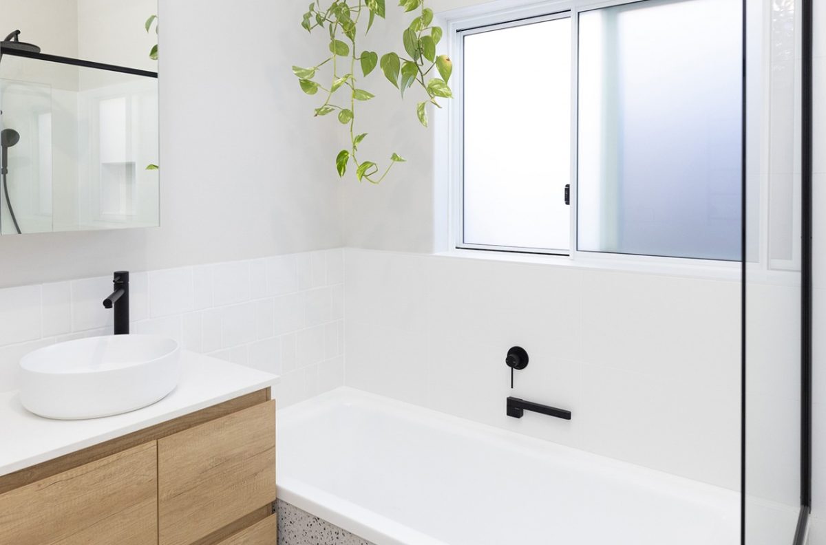 A bathroom with a plant hanging above a renovated bath