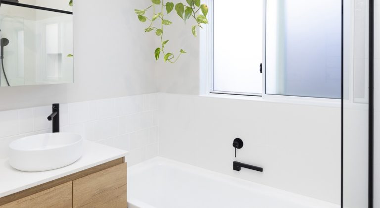 A bathroom with a plant hanging above a renovated bath