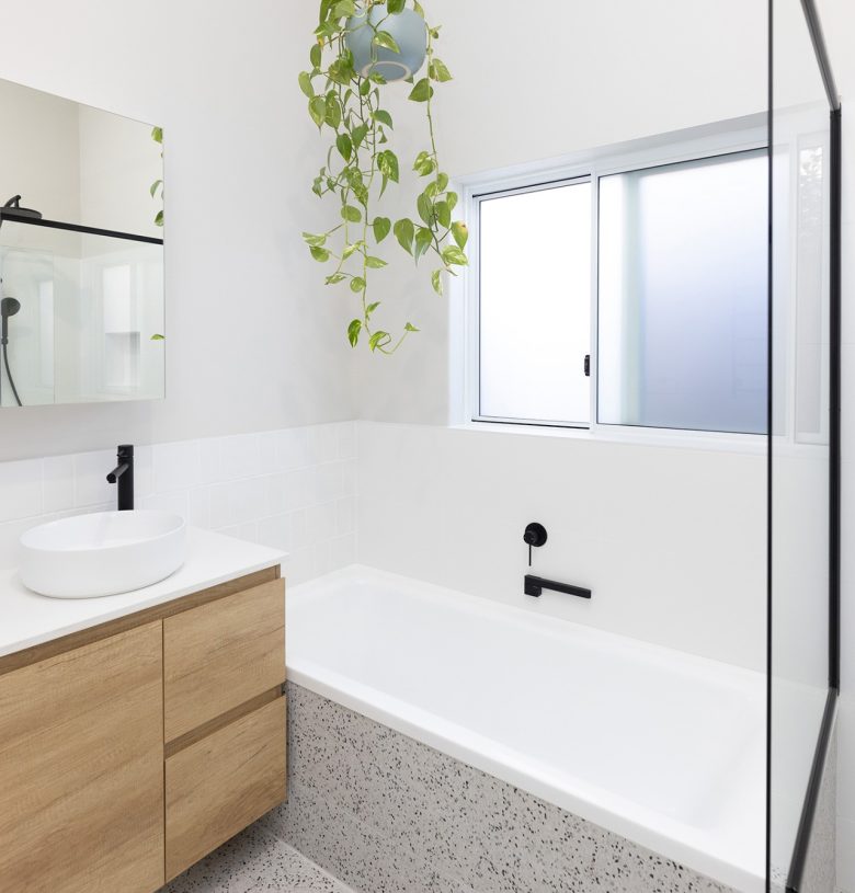 A bathroom with a plant hanging above a renovated bath
