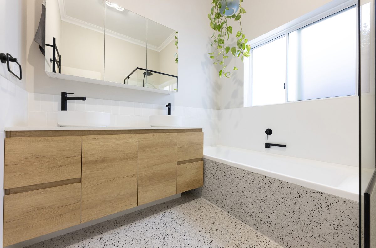 Two sinks side-by-side on a smooth vanity with a bath in the background.