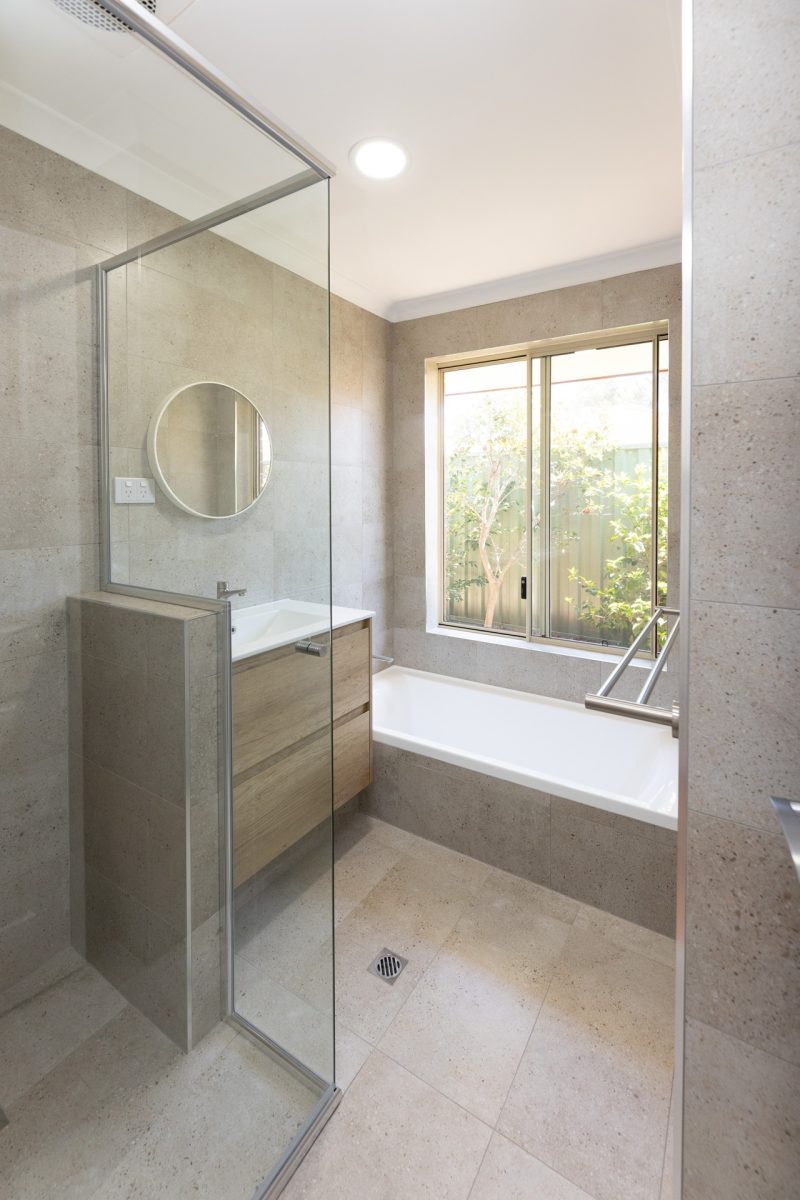 Renovated bathroom with cream coloured tiles, a floating vanity and spacious shower