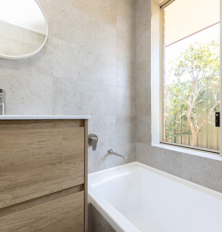 Vanity beside large bath, with a window behind letting natural light in