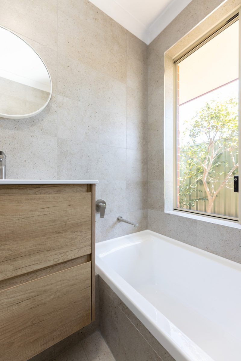 Vanity beside large bath, with a window behind letting natural light in