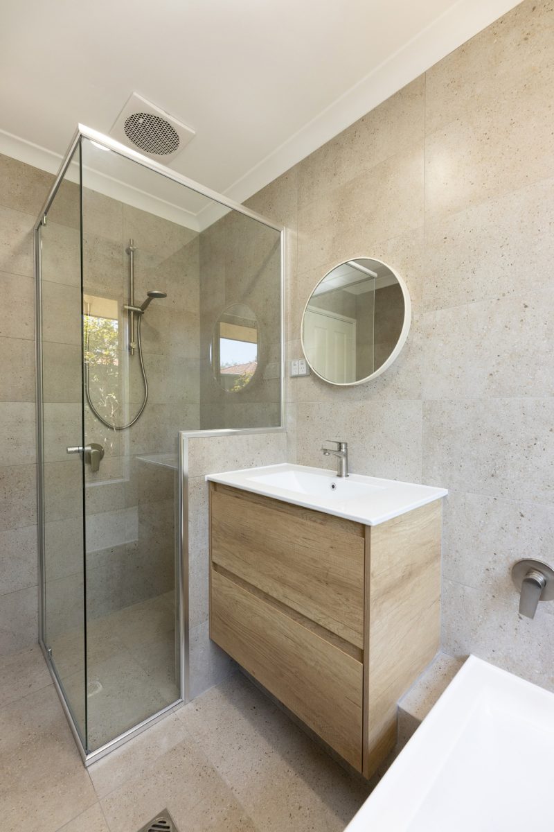 Renovated bathroom with cream coloured tiles, a floating vanity and spacious shower