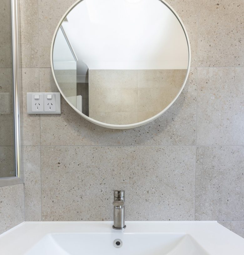 Small, circular mirror in renovated bathroom