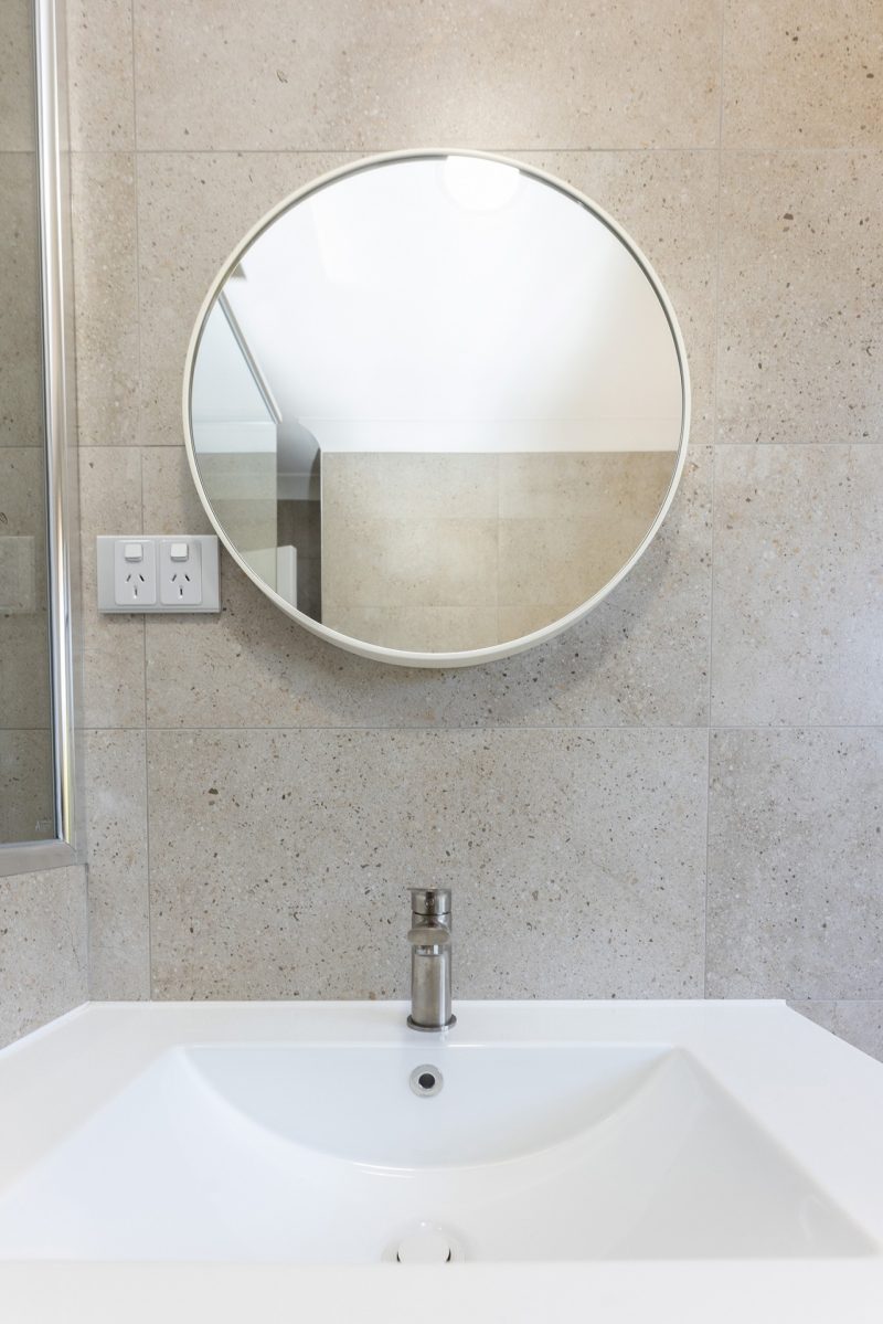 Small, circular mirror in renovated bathroom