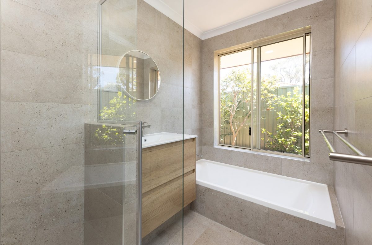 Renovated bathroom with cream coloured tiles, a floating vanity and spacious shower