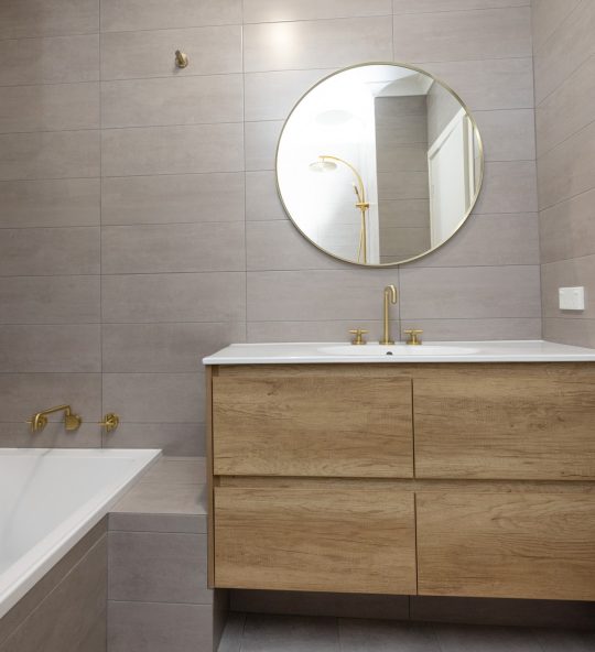 Slate grey bathroom with wide vanity and gold finishings