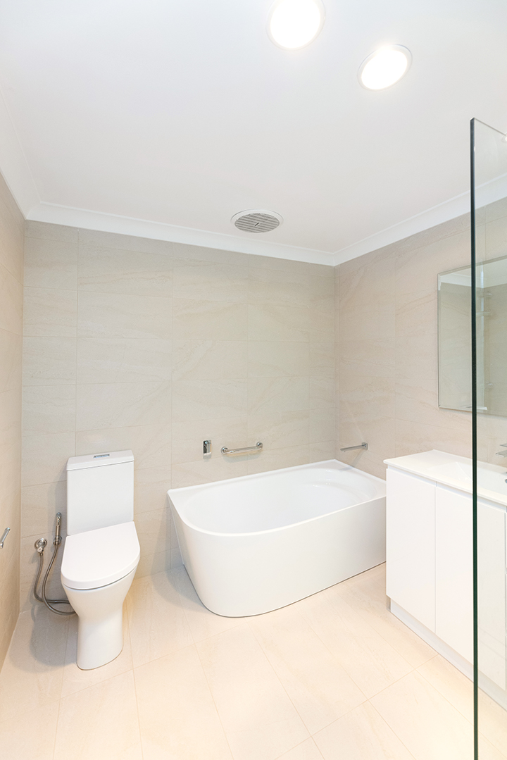 Spacious bathroom, with a toilet, walk in shower and cream coloured tiles