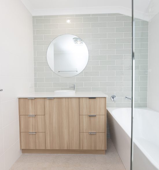 White bathroom and wood-like vanity, with a feature grey brick wall