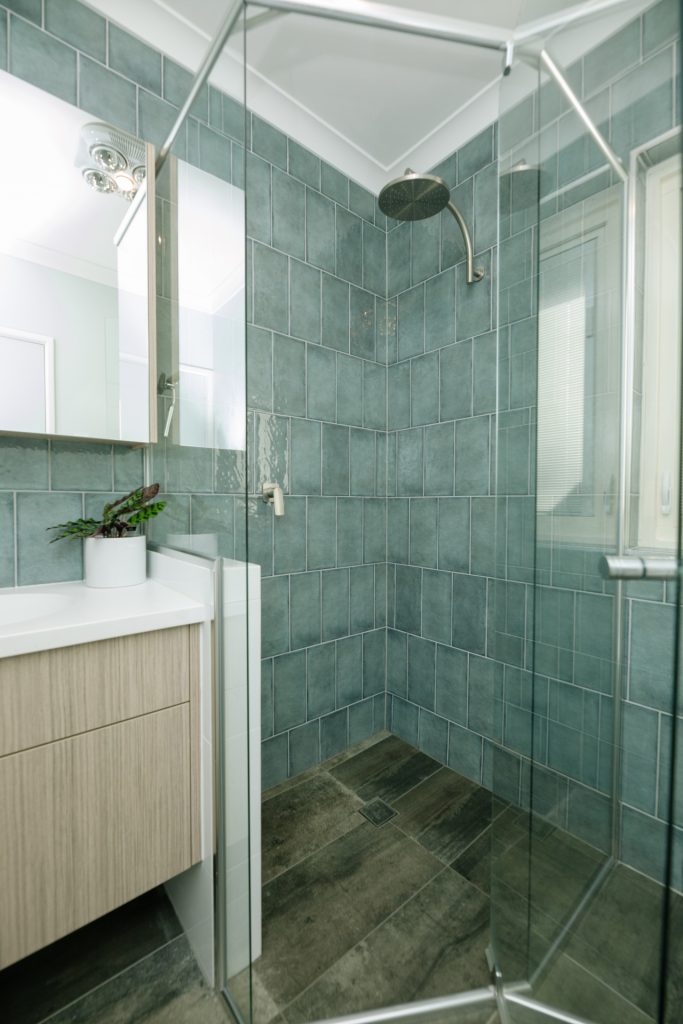 A glass shower enclosure with glossy floor-to-ceiling tiling on its back walls