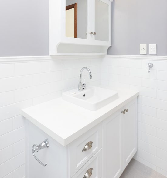 An all-white bathroom renovation with a white vanity and cabinetry