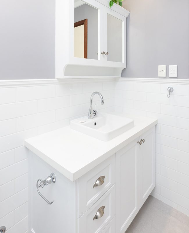 An all-white bathroom renovation with a white vanity and cabinetry
