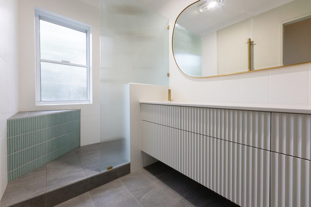 Gold lined mirrors, a vanity and a large spacious shower, with a ledge to sit on
