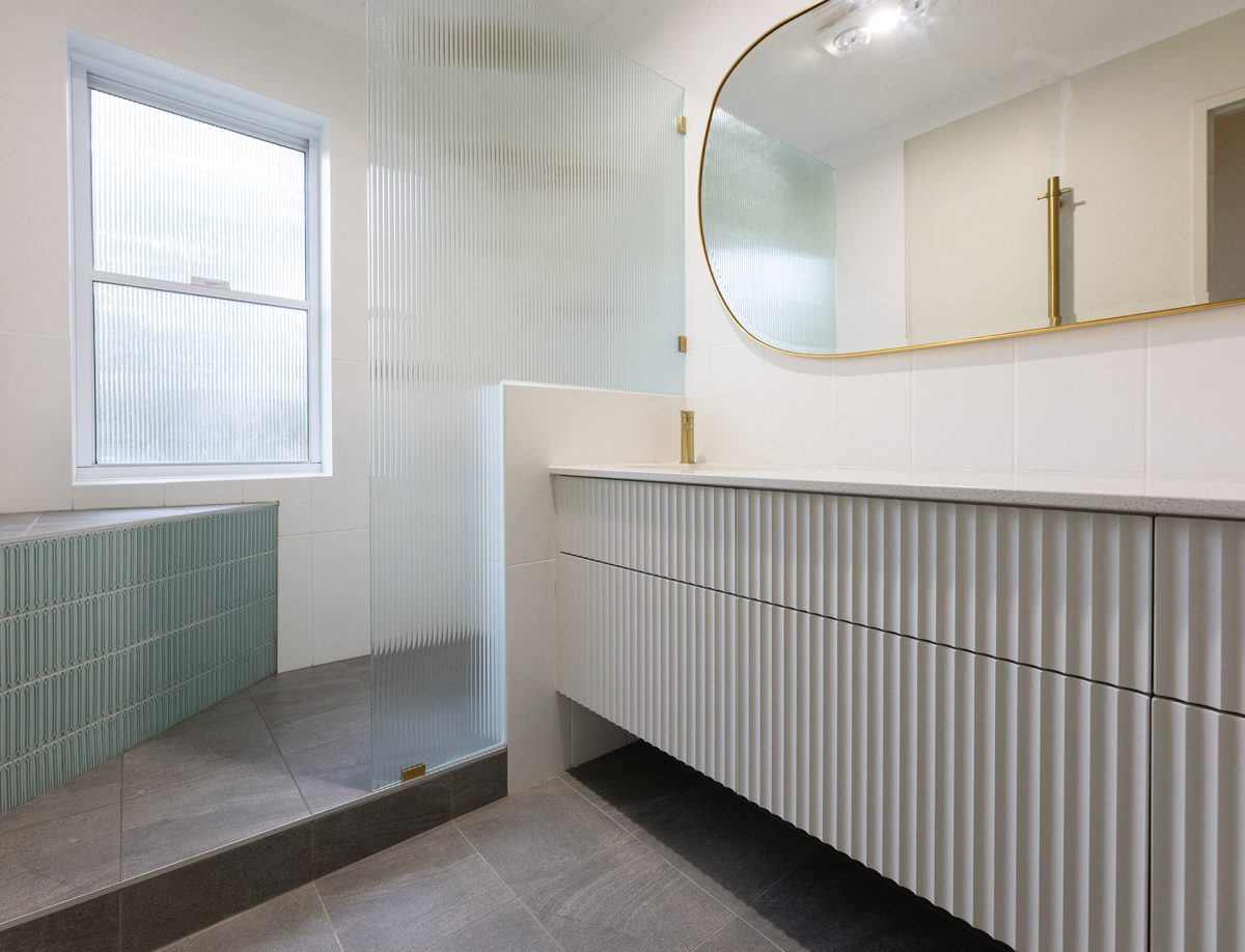 Gold lined mirrors, a vanity and a large spacious shower, with a ledge to sit on