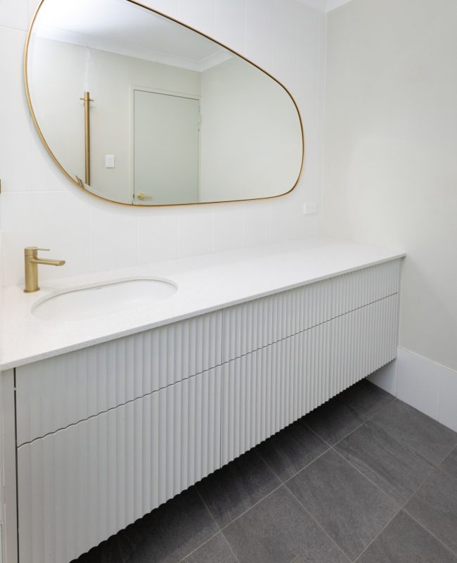 A large gold-edged mirror above a simple but elegant long vanity