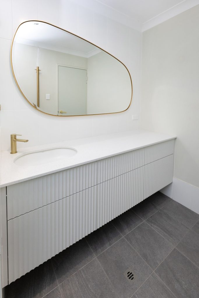 A large gold-edged mirror above a simple but elegant long vanity